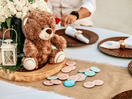 a teddy bear sitting on a table with a vase of flowers