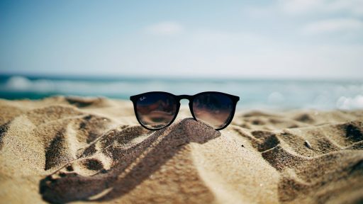 black Ray-Ban Wayfarer sunglasses on beach sand