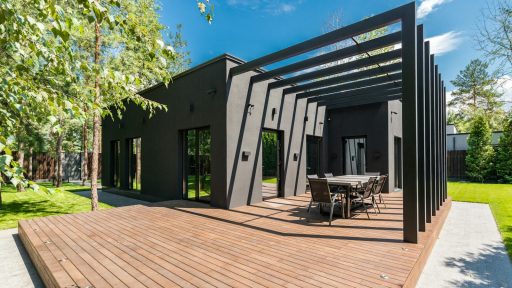 Stylish outdoor space with wooden deck and dining set, surrounded by lush greenery.