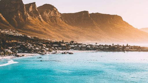photography of buildings beside seashore and mountain during daytime