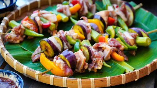 a platter of skewered vegetables and meat on a banana leaf