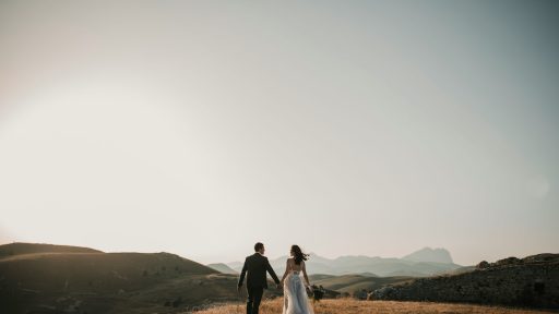 a bride and groom walking on a hill