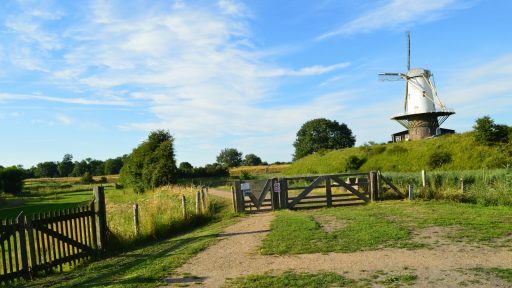 a windmill on top of a hill near a fence