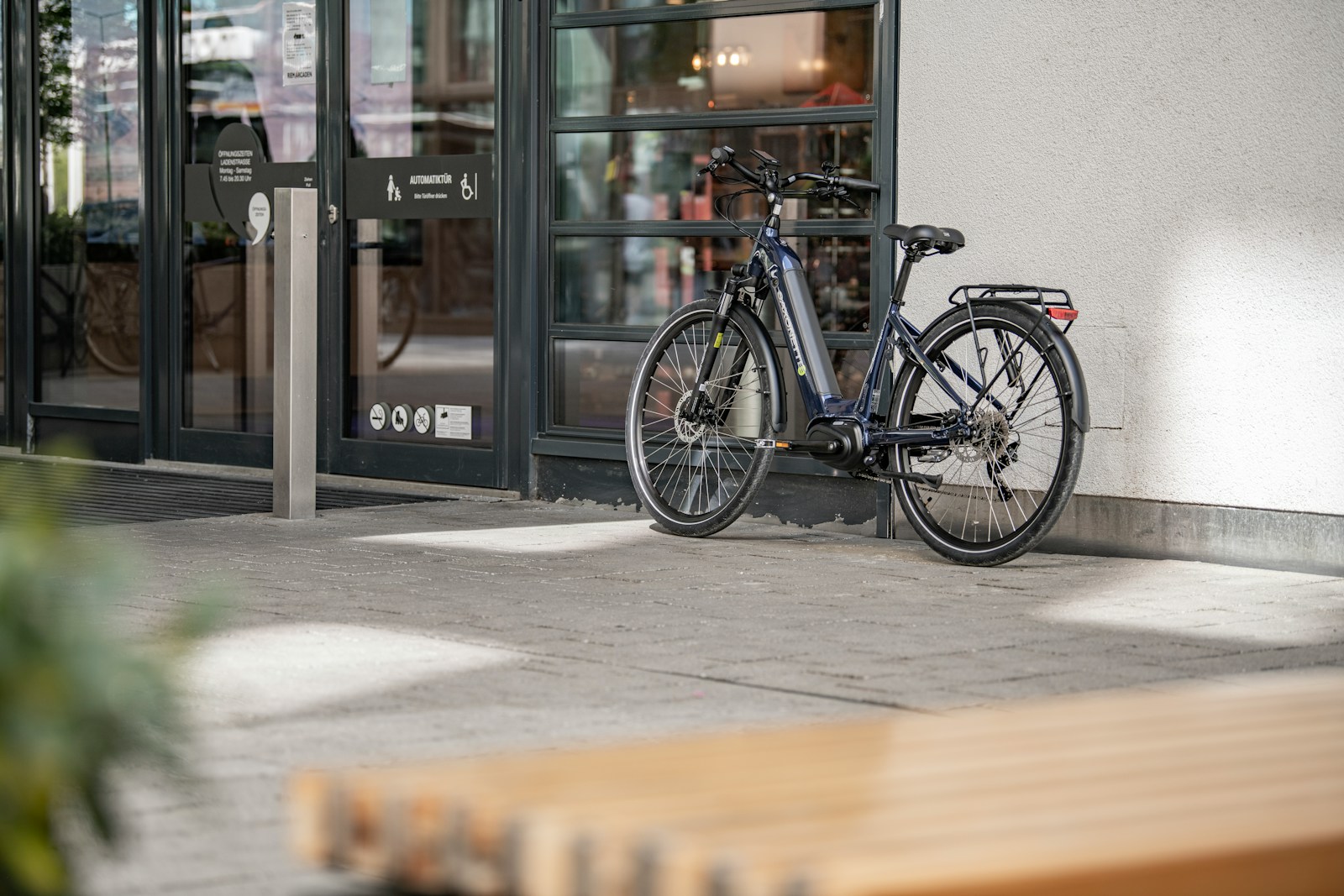 A dark blue bicycle parked by a building.