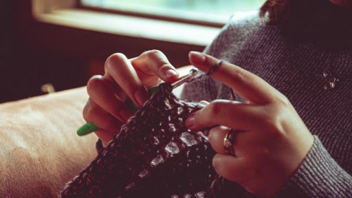person in black knit sweater holding pen