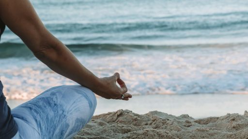 person in blue shorts sitting on beach shore during daytime