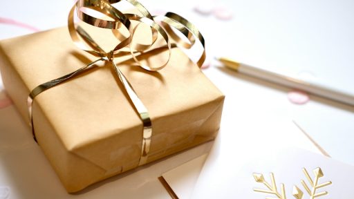 A gift wrapped in brown paper with a gold ribbon.