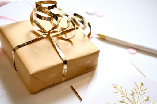 A gift wrapped in brown paper with a gold ribbon.
