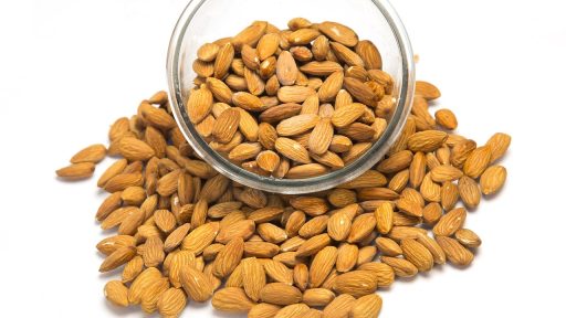 Een houten schaaltje gevuld met pompoenpitten, amandelen en andere noten als rijke bronnen van magnesium via voeding