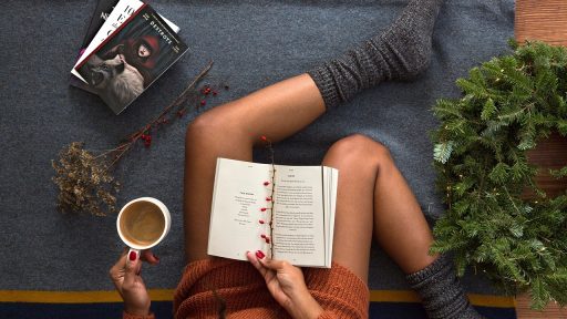 Vrouw leest een boek met een kop koffie in haar handen