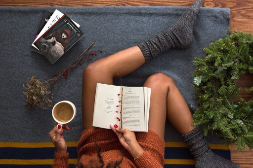 Vrouw leest een boek met een kop koffie in haar handen