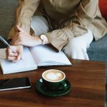 Vrouw schrijft in notitieboekje aan tafel met koffie