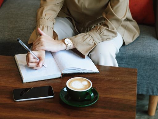 Vrouw schrijft in notitieboekje aan tafel met koffie