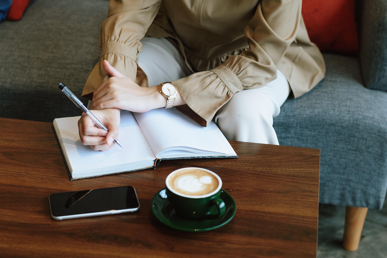 Vrouw schrijft in notitieboekje aan tafel met koffie