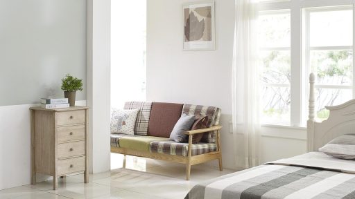 Lichte Scandinavische woonkamer met linnen kussens, houten vloer en een vaas met eucalyptustakken in de zomer
