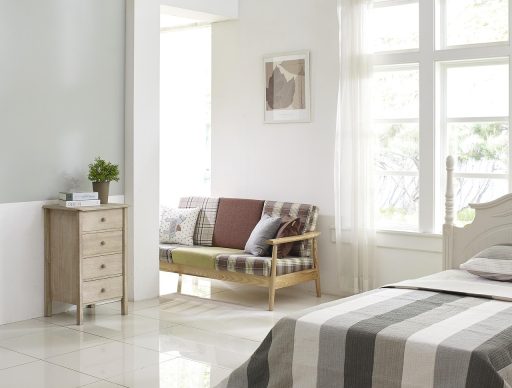 Lichte Scandinavische woonkamer met linnen kussens, houten vloer en een vaas met eucalyptustakken in de zomer