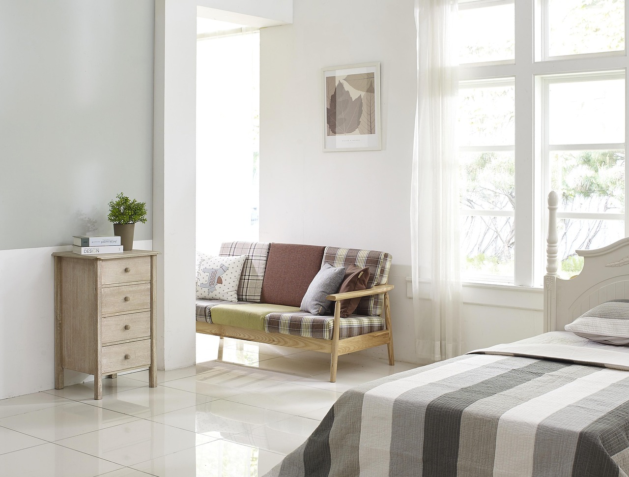 Lichte Scandinavische woonkamer met linnen kussens, houten vloer en een vaas met eucalyptustakken in de zomer