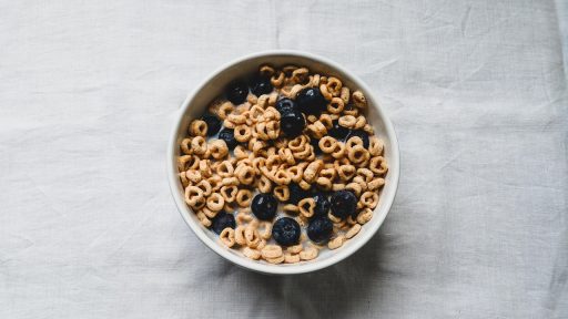 Kom gevuld met vezelrijke voeding zoals haver, linzen, noten en fruit op een houten tafel