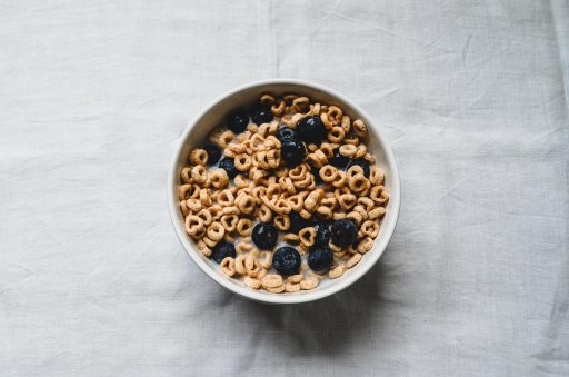 Kom gevuld met vezelrijke voeding zoals haver, linzen, noten en fruit op een houten tafel