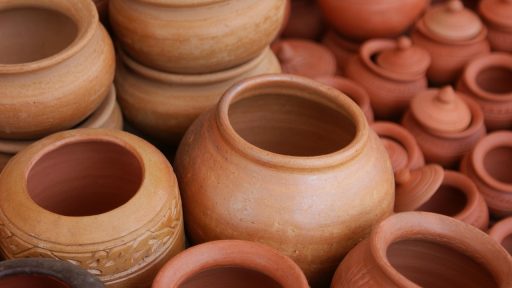 Een keramist werkt aan een pot in een landelijk atelier met klei en handgereedschap op tafel