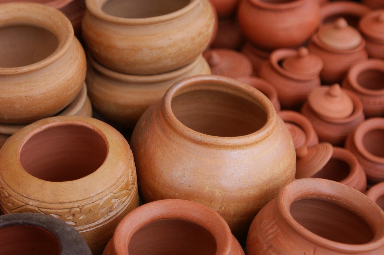 Een keramist werkt aan een pot in een landelijk atelier met klei en handgereedschap op tafel