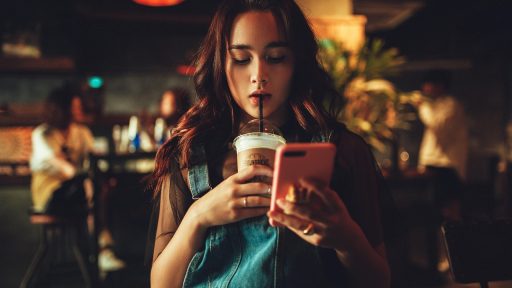 Vrouw scrolt 's avonds op haar telefoon, klaar om iets te kopen in een webshop