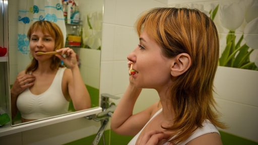Vrouw kijkt nadenkend naar zichzelf in een badkamerspiegel