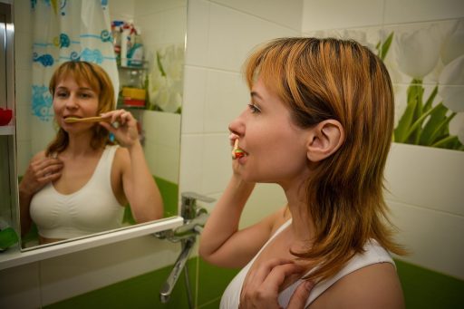 Vrouw kijkt nadenkend naar zichzelf in een badkamerspiegel