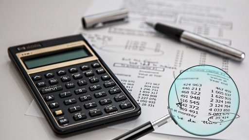 Vrouw aan tafel die haar financiële overzicht bekijkt met papieren en een laptop