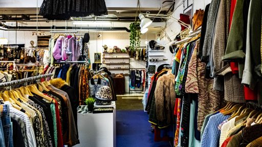 Kleurrijke rekken met vintage kleding in een kleine tweedehandswinkel
