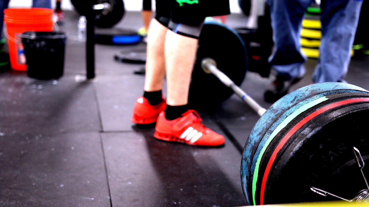 Een vrouw die geconcentreerd een barbell optilt in een sportschool