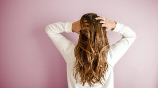 woman in white long-sleeved shirt standing in front of pink wall