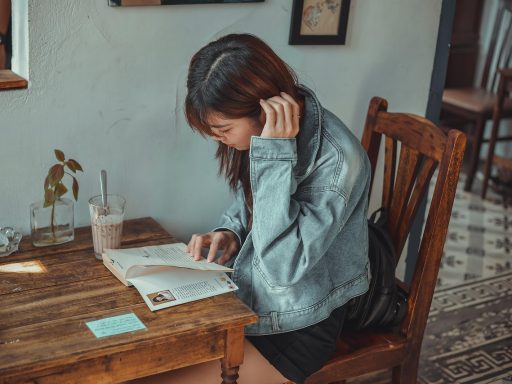 Een vrouw leest een boek aan een tafeltje in een rustig café