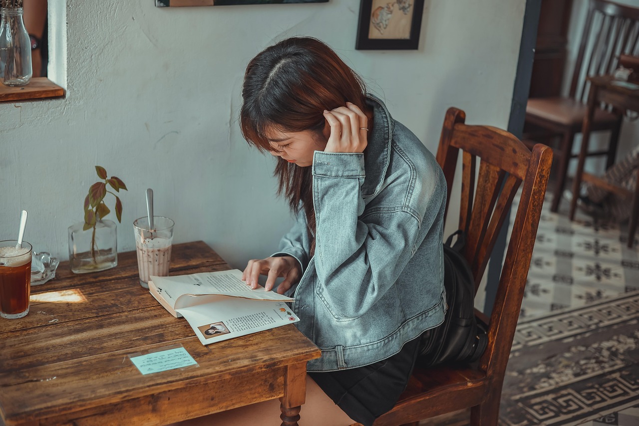 Een vrouw leest een boek aan een tafeltje in een rustig café