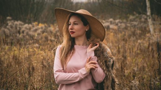 Vrouw die herfstkleding sorteert en stapelt op haar bed
