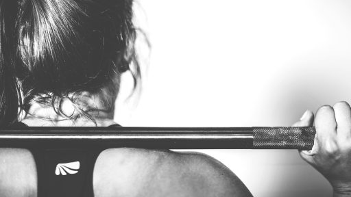 Vrouw in sportkleding die een squat maakt in de sportschool