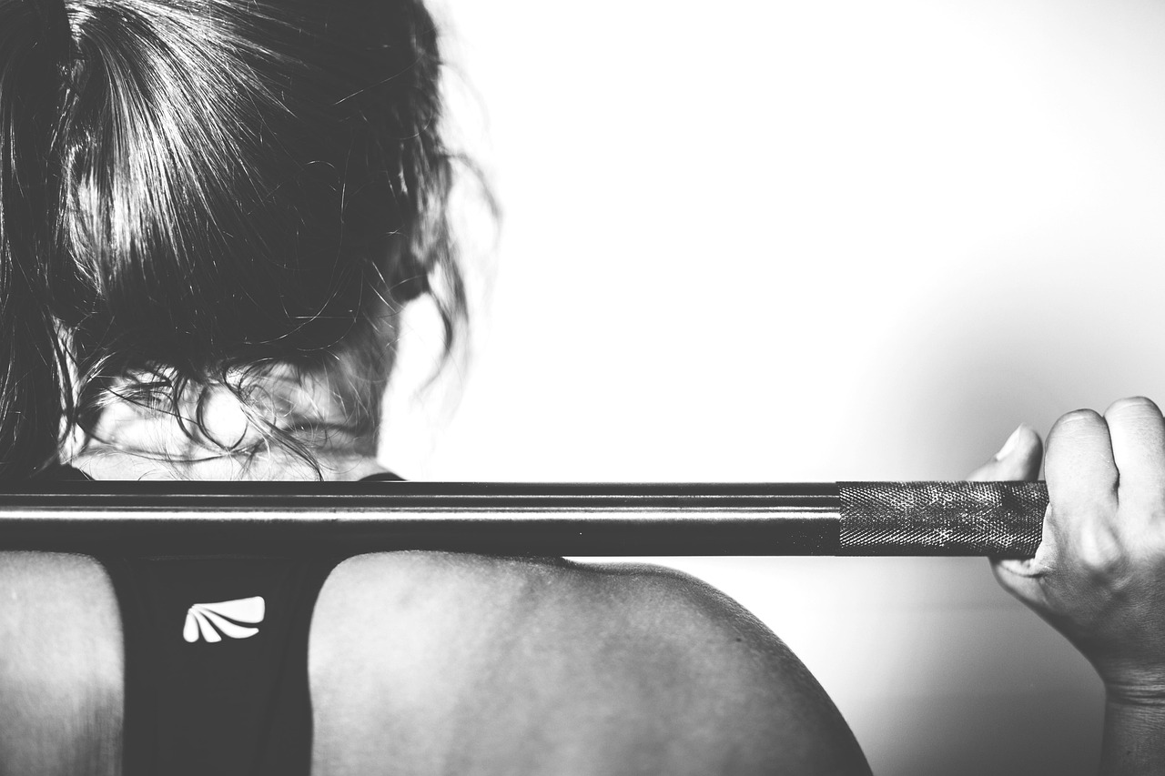 Vrouw in sportkleding die een squat maakt in de sportschool