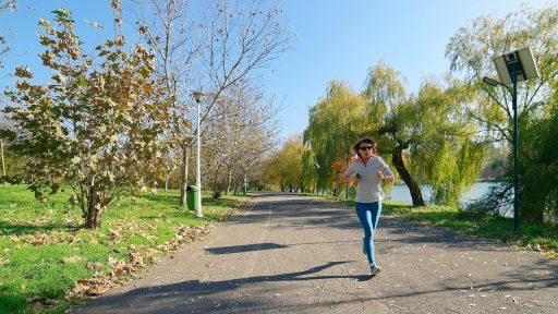 Vrouw hardloopt in een herfstpark met gevallen bladeren op de grond