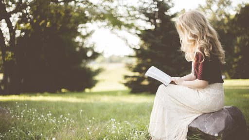 Een vrouw leest geconcentreerd een thriller met een donkere omslag