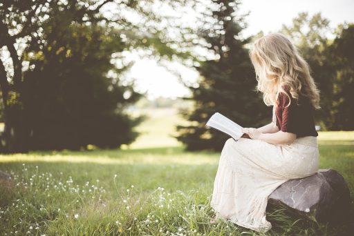 Een vrouw leest geconcentreerd een thriller met een donkere omslag