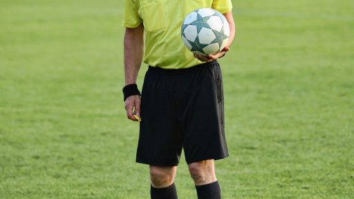 Een vrouwelijke scheidsrechter loopt zelfverzekerd het voetbalveld op tijdens een wedstrijd