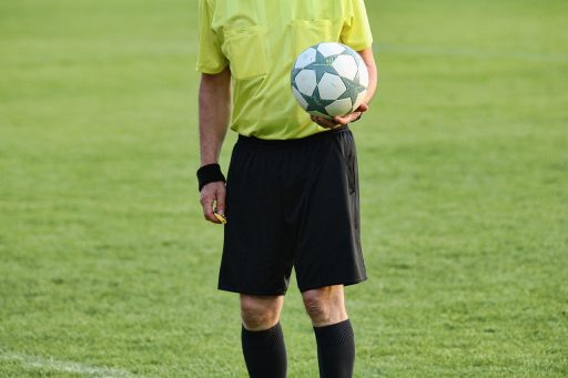 Een vrouwelijke scheidsrechter loopt zelfverzekerd het voetbalveld op tijdens een wedstrijd
